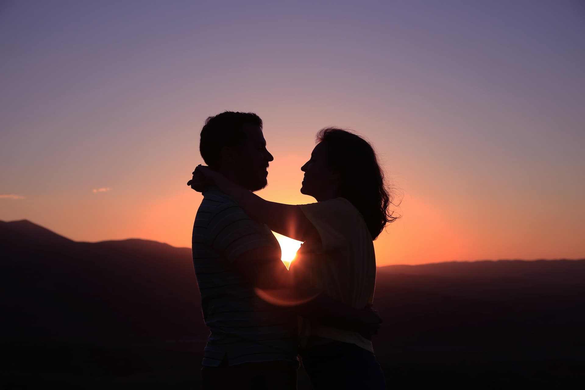 A couple on a hillside terrace overlooking the Napa Valley vineyards at golden hour