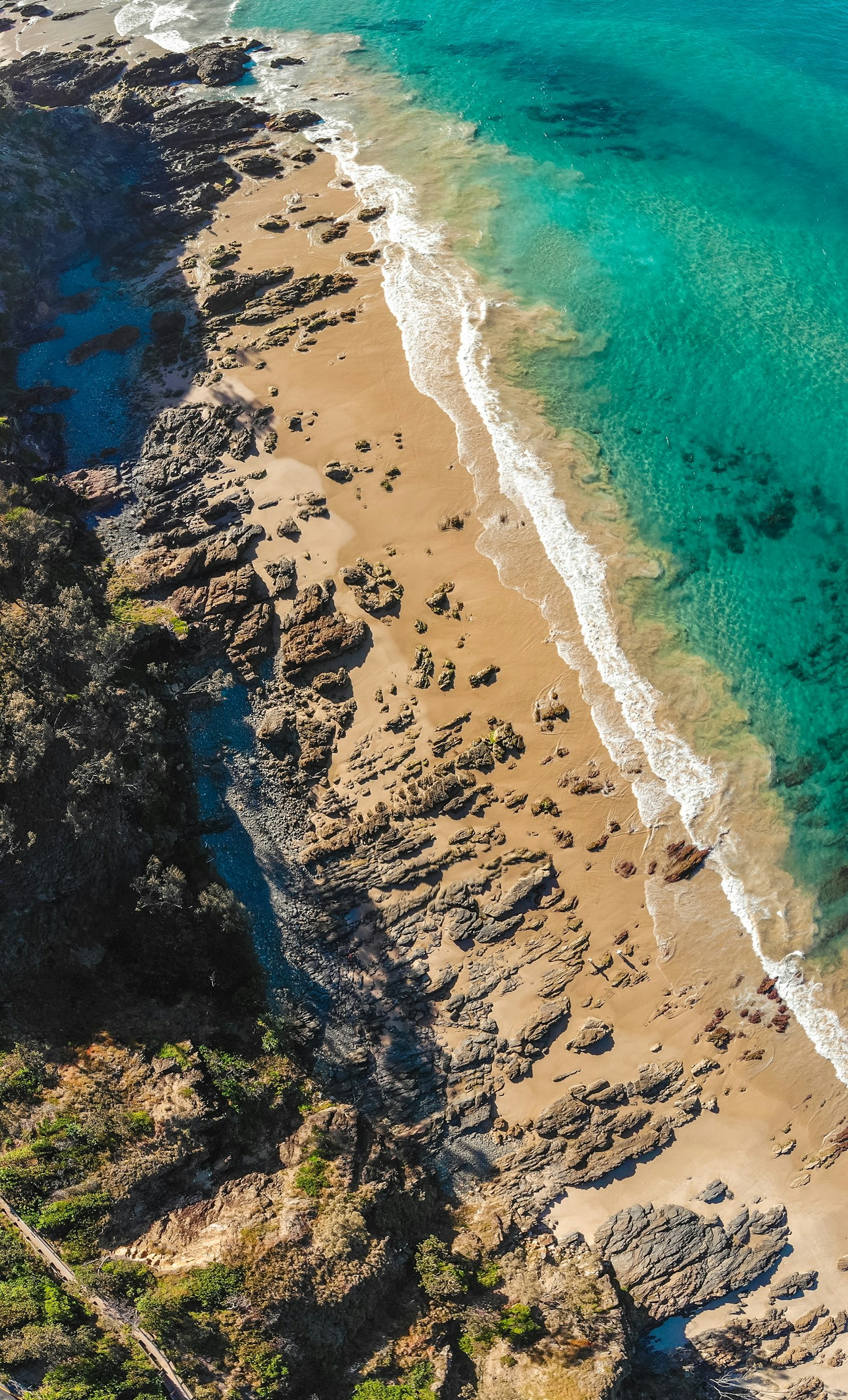 A coastal road winding along dramatic cliffs above the Pacific at golden hour
